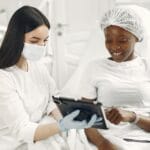 Dermatolog z uśmiechniętą pacjentką omawiają plan zabiegu na tablecie