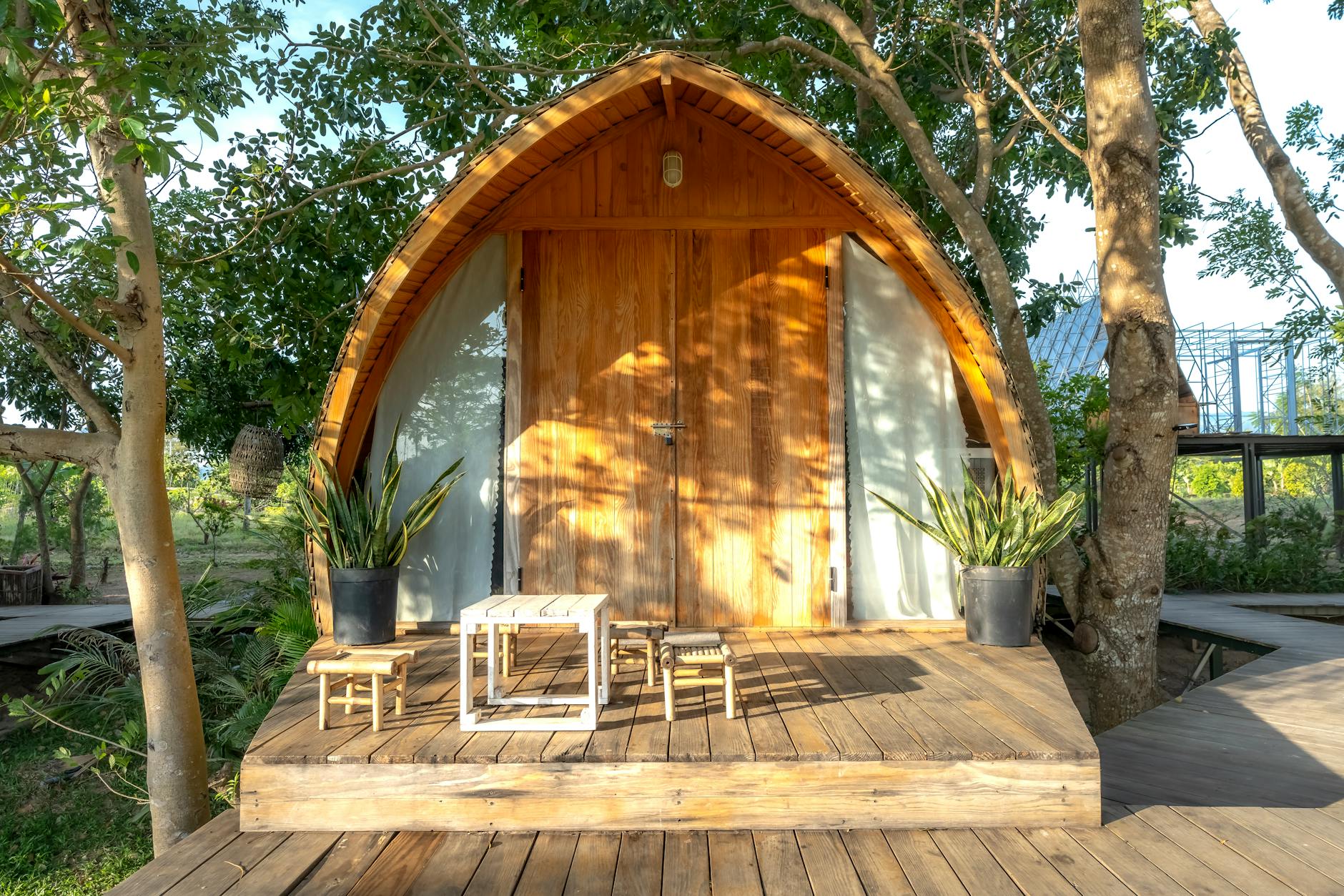 Drewniany domek letniskowy z tarasem pośród zieleni za dnia