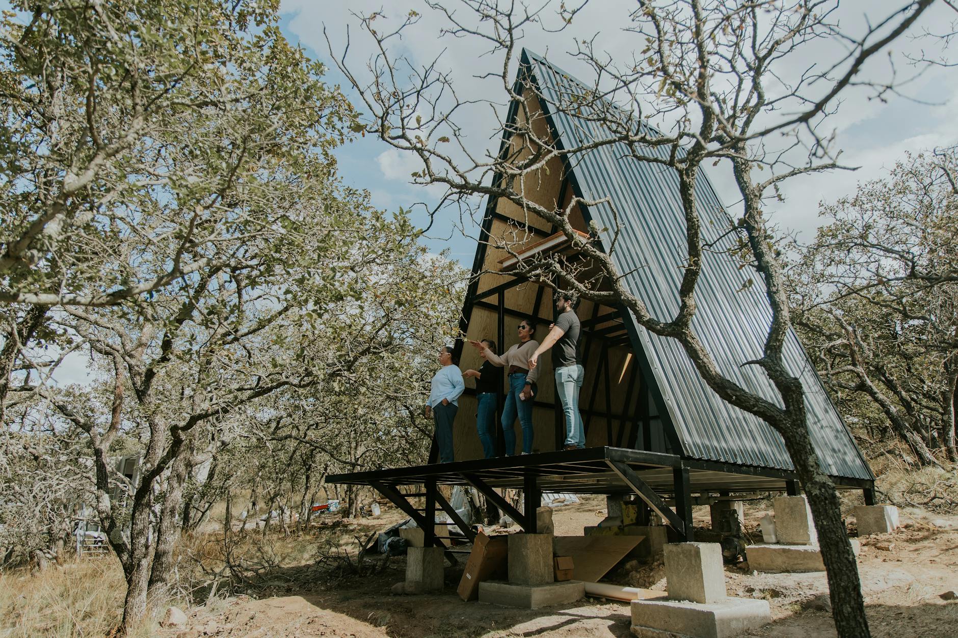 Grupa osób buduje nowoczesny domek typu A w lesie na działce rekreacyjnej