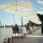 Letnia nadmorska restauracja z białymi parasolami i pustymi stolikami