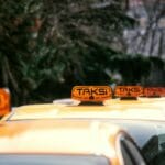 Rząd żółtych taksówek z napisem Taksi stojących wzdłuż miejskiej ulicy