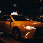 Żółta taksówka nocą na ulicy oświetlonej latarniami