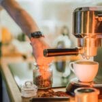 Barista przygotowuje espresso na profesjonalnym ekspresie ciśnieniowym