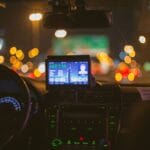 Nocny przejazd taksówką, zbliżenie na licznik i ekran na tle świateł miasta