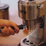 Osoba przygotowuje espresso na domowym, stalowym ekspresie