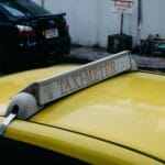 Żółta taksówka z podświetlonym szyldem taxi na dachu w mieście