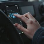 Dłoń obsługuje nawigację GPS w smartfonie zamocowanym w aucie