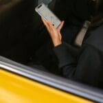 Kobieta w żółtej taksówce sprawdza mapę w telefonie