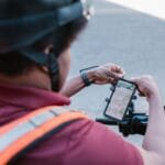 Kurier na skuterze sprawdza trasę w smartfonie na uchwycie