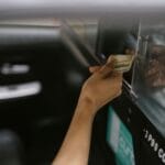 Pasażer płaci gotówką kierowcy taxi po zakończonym kursie