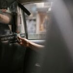 Pasażer w taksówce płaci kartą w terminalu kierowcy